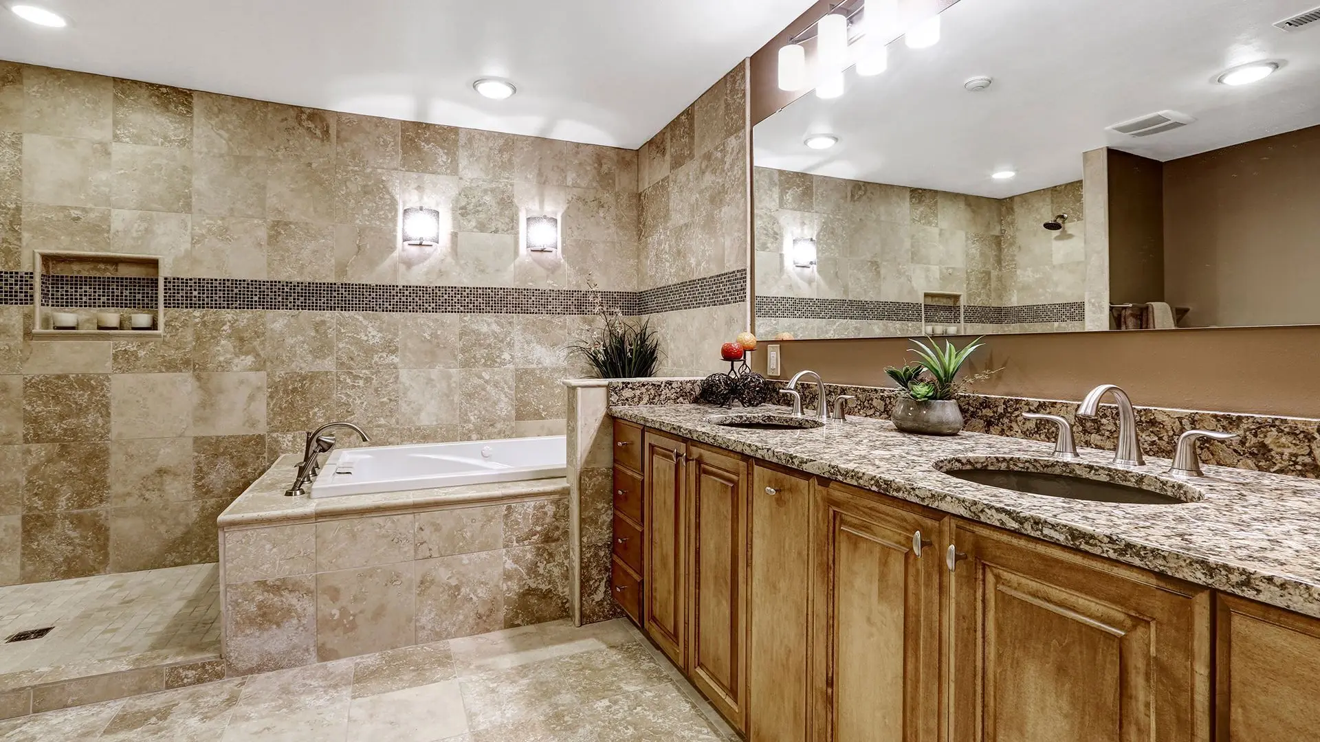 Travertine tile bathroom with a soaking tub, double granite vanity and mosaic accent band